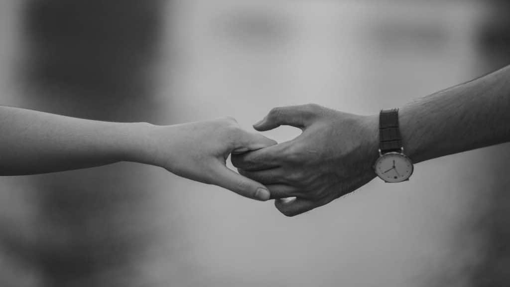 A man and a woman's hands clasped together in a black and white photo, symbolizing trust and healing after relationship struggles.